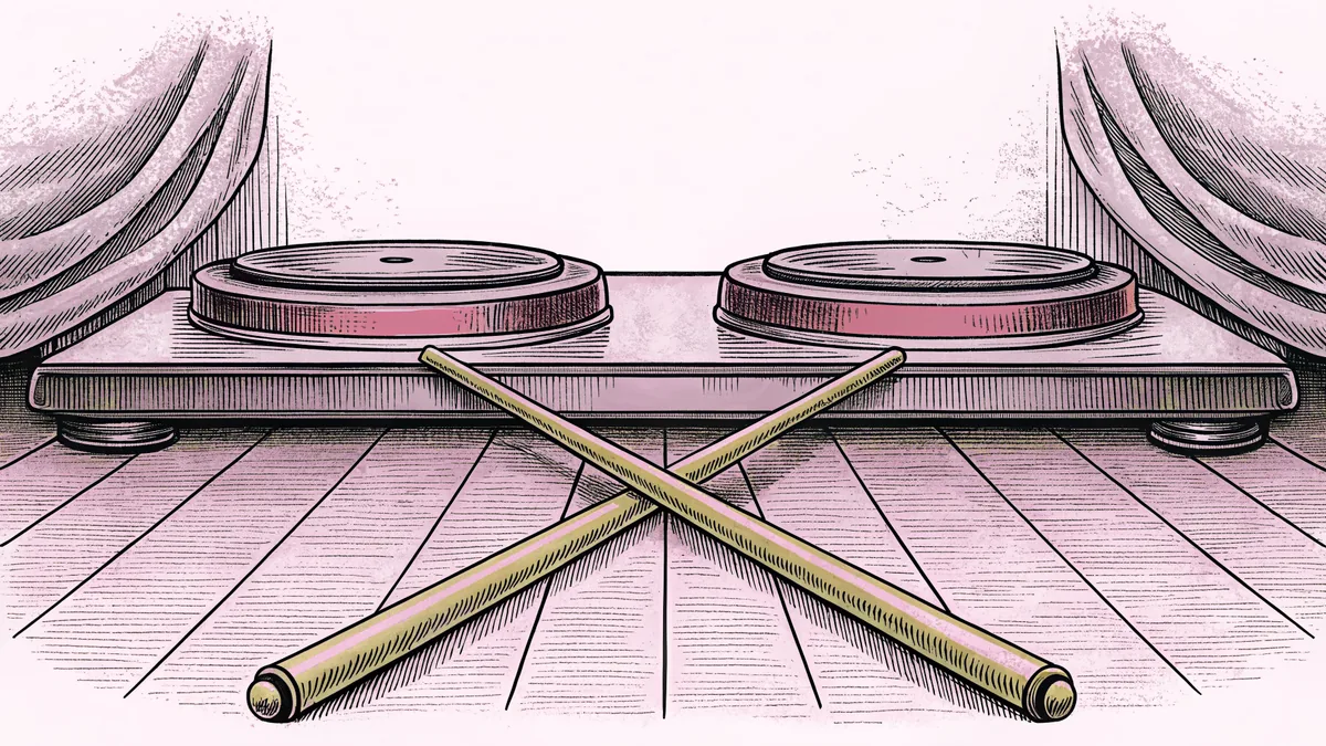 A turntable tonearm resting above a record, beside a pair of drumsticks on a scuffed floor.