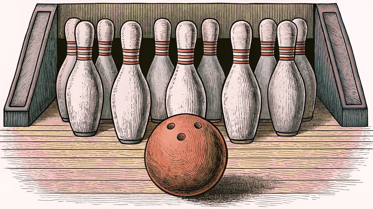 A polished bowling ball rests near white pins on a wooden lane beside a scoreboard.
