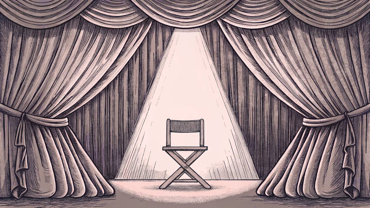 A director's chair faces a stage, bathed in warm spotlight light against a burgundy velvet curtain.