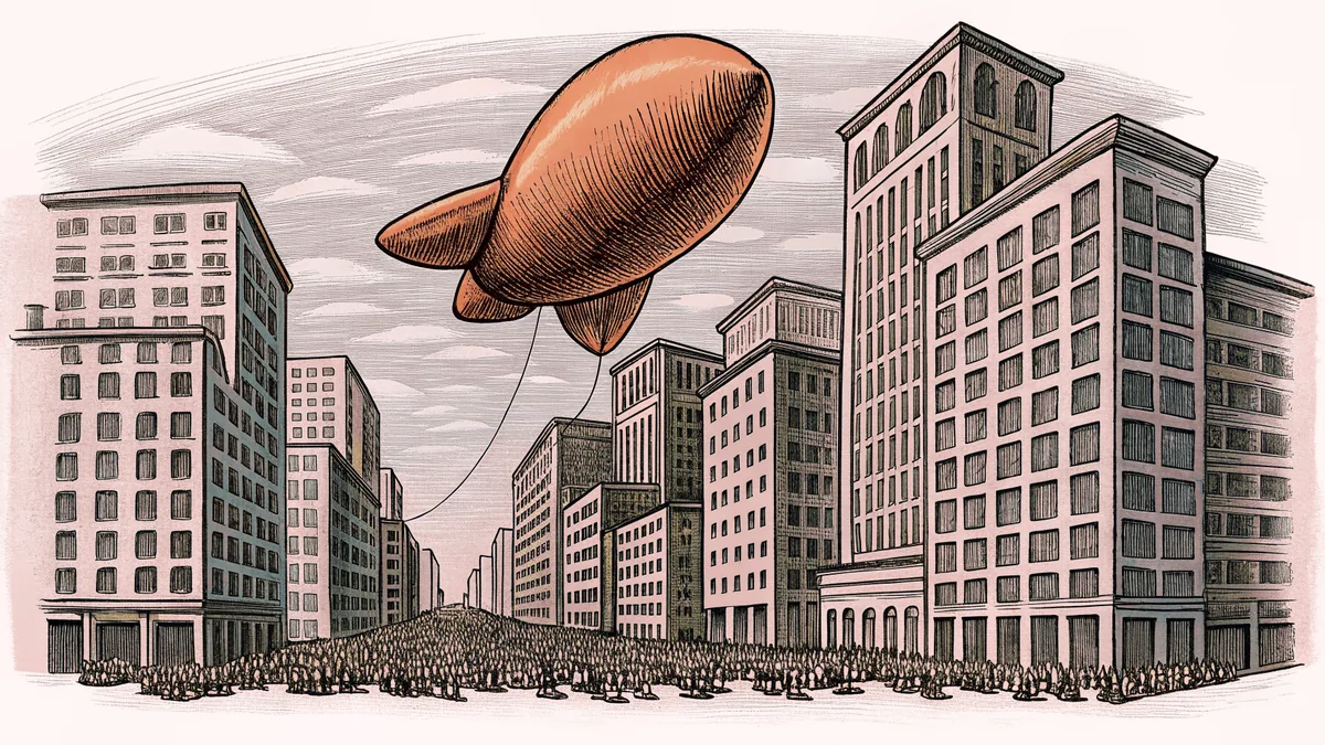 A colossal character balloon hovers over city buildings as parade marchers pass underneath on the street.