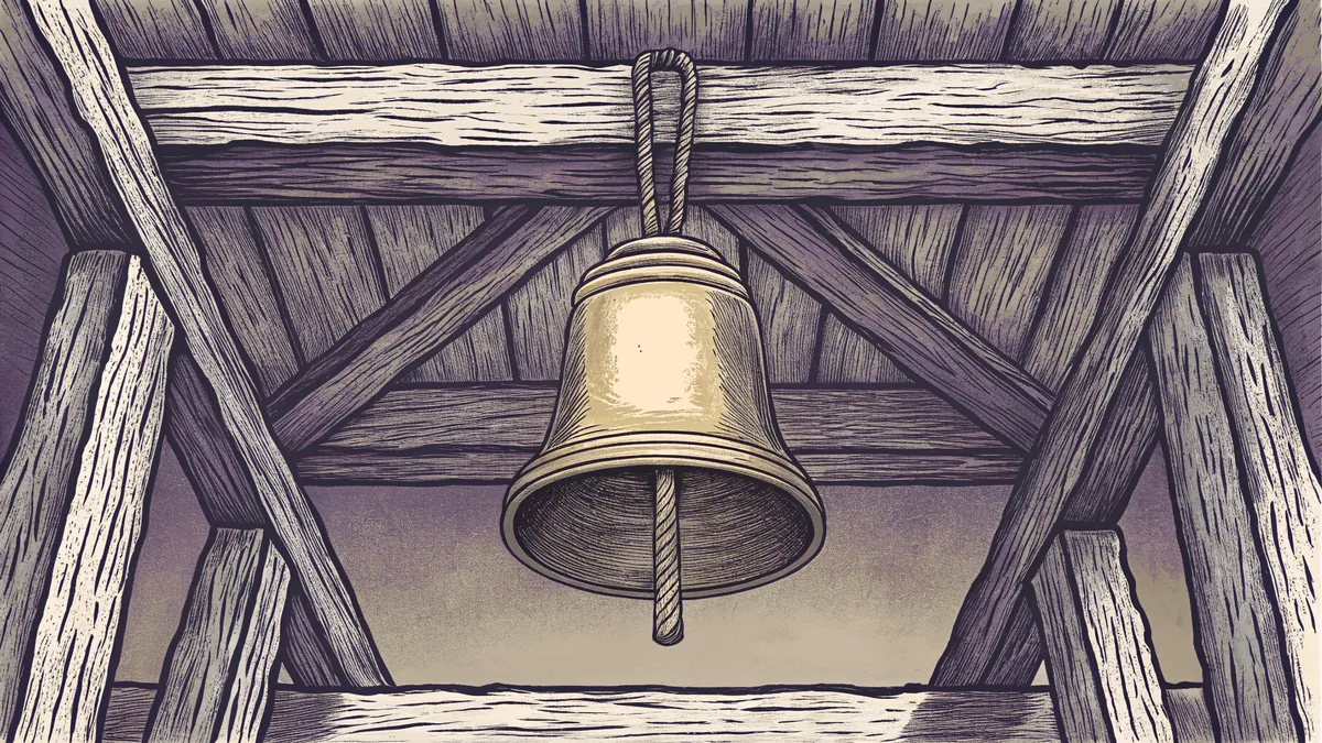 A large cast brass bell hanging from a rope looped over a heavy timber crossbeam.