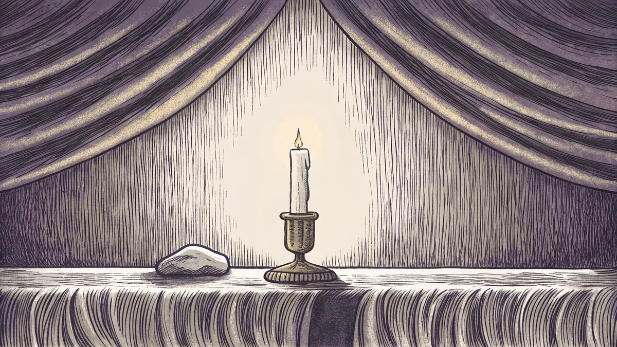 A single stone rests on a memorial ledge beside a softly lit candle in a quiet room.