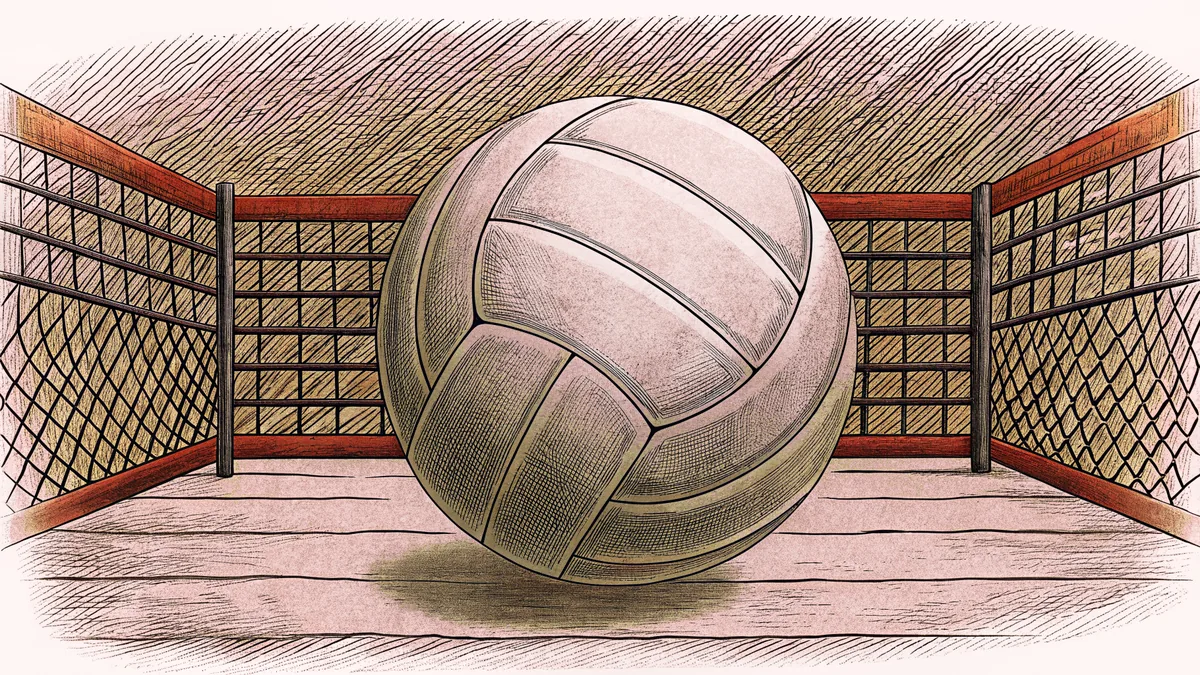 A volleyball floats above the net on a sandy court with white boundary lines.