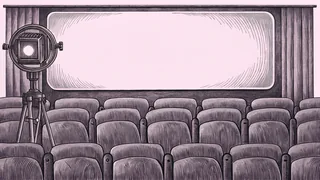An on-air lamp and remote control sit beside a cinema seat row on a stage.