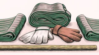 A folded martial arts belt and training gloves rest beside a wooden staff in a dojo.