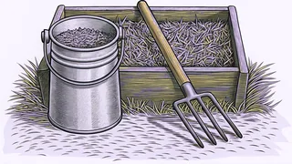 A pitchfork with a wooden handle and a tin feed pail stand beside a wooden trough filled with straw.