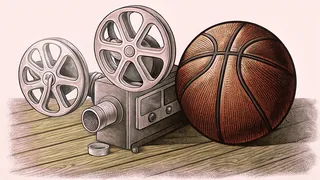 A vintage movie projector sits beside a basketball on a wooden gym floor.