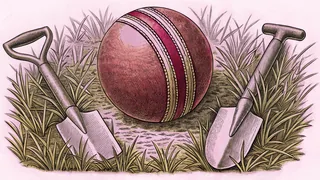 A stitched leather ball resting on dry grass beside two small garden spades.