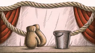 A pair of red boxing gloves lies on canvas beside thick ring ropes with a water bucket.