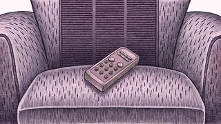 A remote control sits on an armchair beside an old-fashioned rabbit-ear antenna.