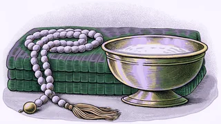 A beaded rosary coiled on folded cloth beside a footed brass bowl.
