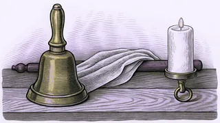 A brass hand bell beside a lit candle in a holder, with a cloth-draped rod between them.