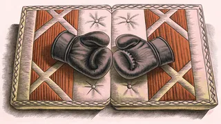 Black boxing gloves rest on a red martial arts mat with a foam training pad.