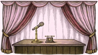 A brass microphone stands beside a candlestick telephone on a wooden broadcast table.