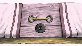 A small brass key lying beside an old keyhole plate on a worn wooden floorboard.
