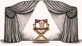 A director's chair positioned in front of theater curtains with stage lighting above popcorn.