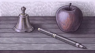 A brass school bell, a fountain pen and a red apple rest together on a dark wooden desk.