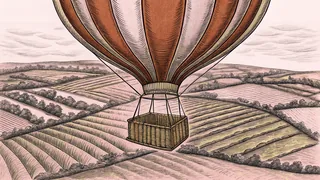 A vibrant hot air balloon rises above farmland with a wicker basket floating beneath.