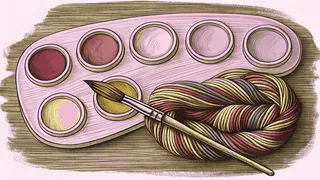 Five paint pots in vivid hues sit on an artist's palette beside rainbow-colored yarn bundles.
