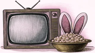 A rabbit-ear antenna sits beside a vintage TV set with popcorn on a table.