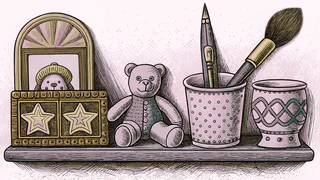 A paintbrush stands in a ceramic cup beside a wound music box and porcelain figurines on a pastel nursery shelf.