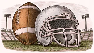 A football and helmet rest on green grass under towering stadium lights.