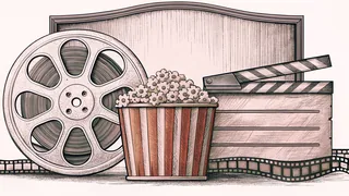 A film reel and blank clapper board sit atop a counter with a striped popcorn container nearby.