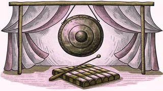 A shiny brass gong hangs above a wooden xylophone with drumsticks on a concert stage.