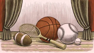 Multiple sports balls and a racquet sit on a polished wooden gymnasium floor.