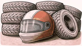 A racing helmet resting on a car's rear spoiler beside a stack of slick tires.