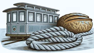 A cable car with rows of windows sits beside a round crusty loaf of sourdough bread and a thick coil of rope.