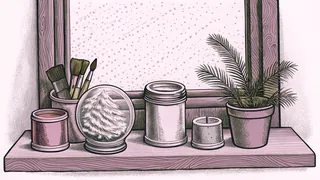 Paint pots and brushes rest beside a snow globe on a windowsill.