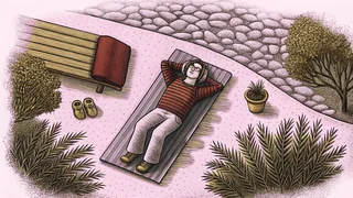 Person relaxing outdoors with headphones enjoying music on a garden path.