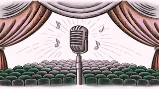 A concert stage with an illuminated microphone, red lighting, and empty audience seats.