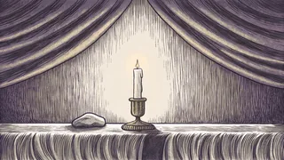 A single stone rests on a memorial ledge beside a softly lit candle in a quiet room.