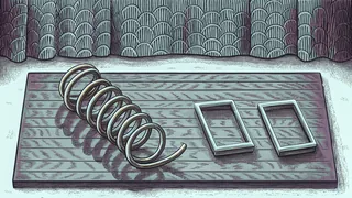 A coiled brass spring beside two rectangular glass frames on a slate surface.